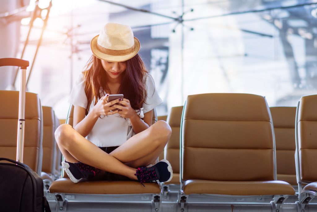 Viajera usando el móvil en el aeropuerto
